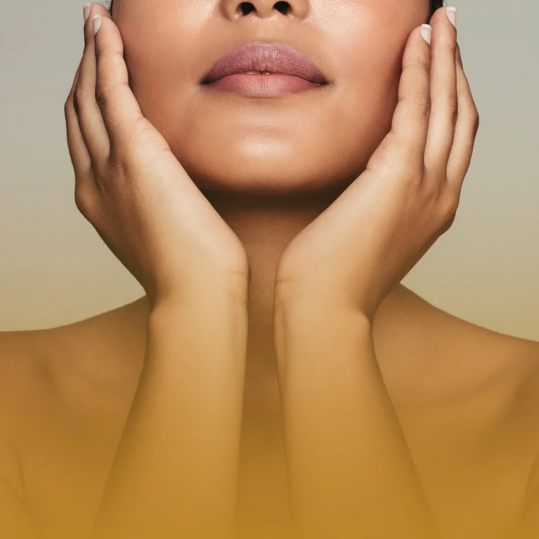 Rosto feminino em close com as mãos apoiadas no contorno facial